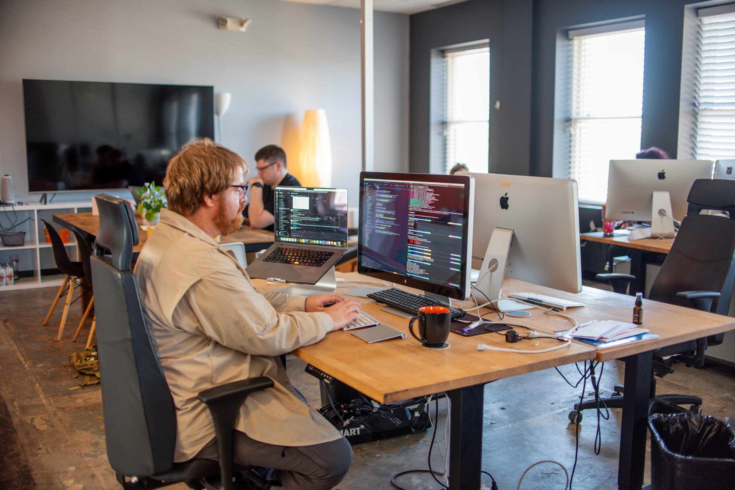 A developer working with code on two monitors in the open office
