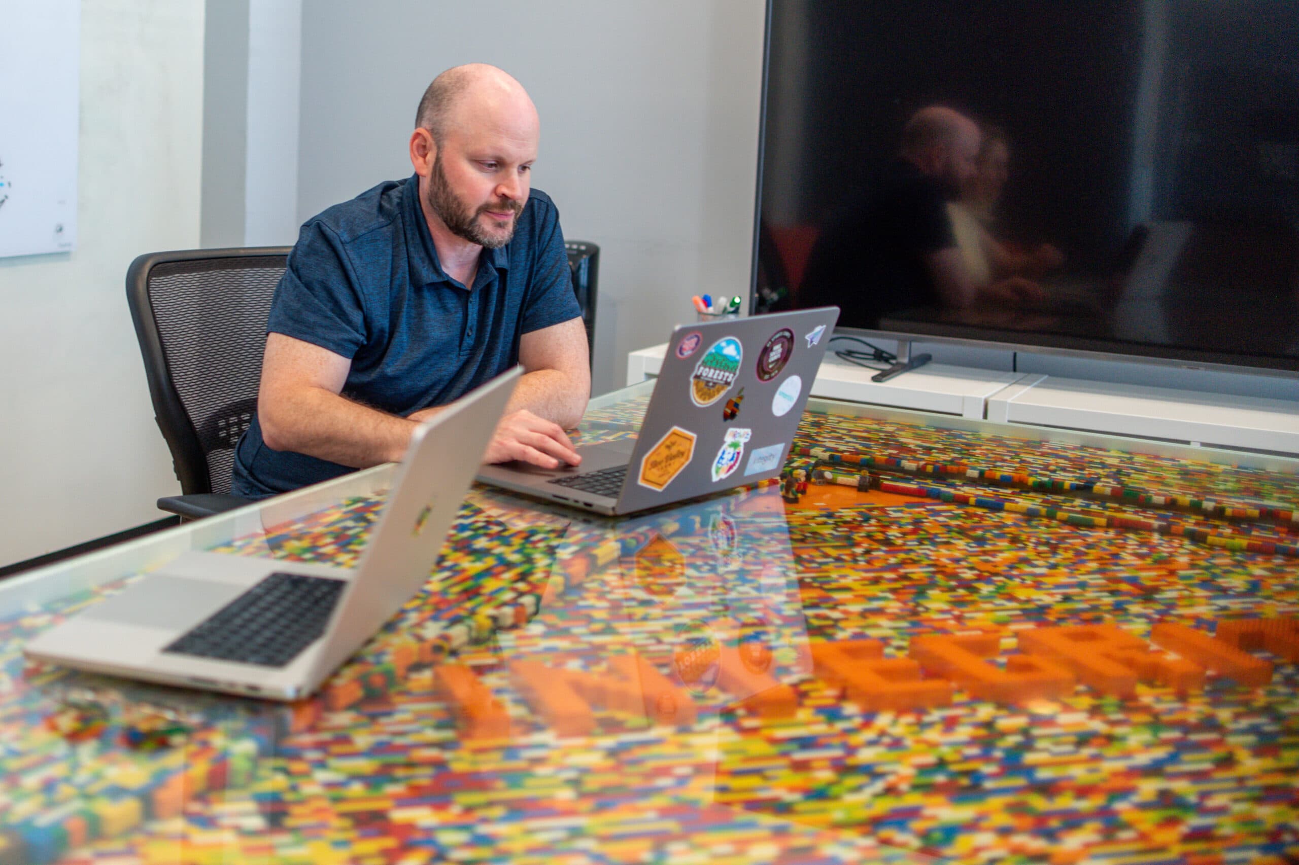 A team member working on laptops at a table inlaid with colorful toy bricks